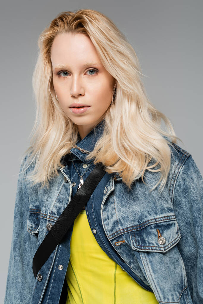 νεαρή ξανθιά μοντέλο με μπλε μάτια κοιτάζοντας κάμερα απομονωμένη σε γκρι  - Φωτογραφία, εικόνα