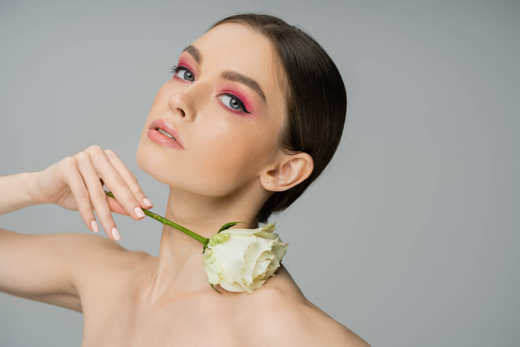 sensual woman with makeup and naked shoulder posing with ivory rose isolated on grey - Photo, image
