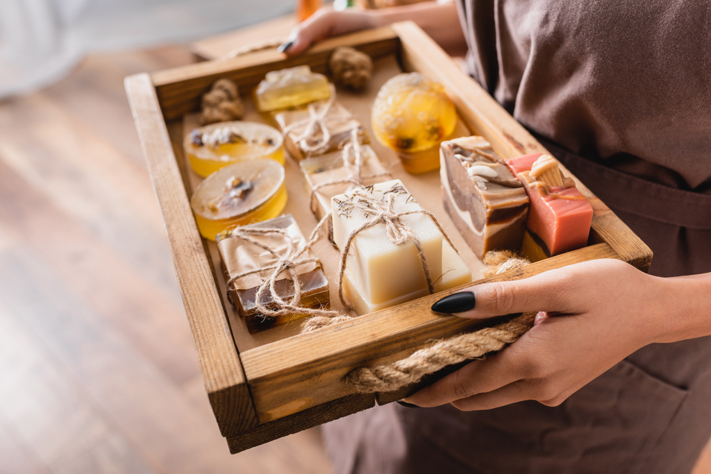 wooden tray with assortment of handmade soap in hands of cropped african american craftswoman - Foto, Bild