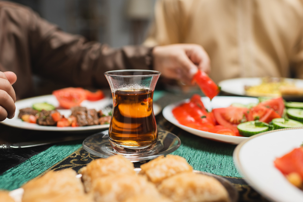 copo de chá turco perto de comida e menino muçulmano durante o jantar no ramadã  - Foto, Imagem