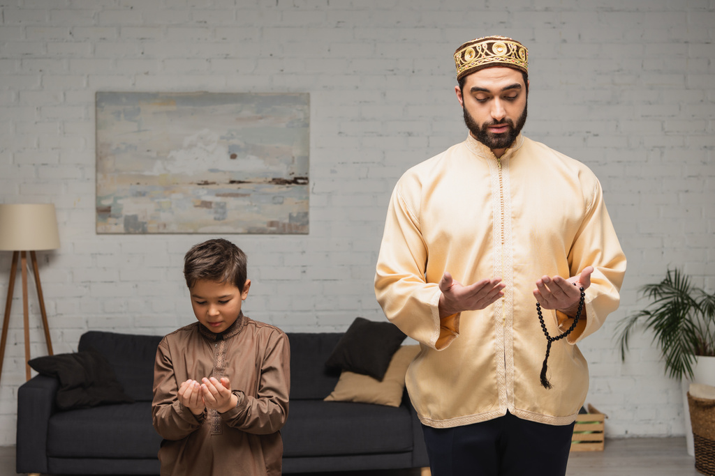 Bliskowschodni mężczyzna i dziecko modlący się podczas salah w domu  - Zdjęcie, obraz
