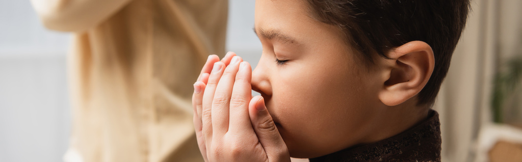 Bambino musulmano che prega vicino ai genitori sfocati durante la salah a casa, striscione  - Foto, immagini