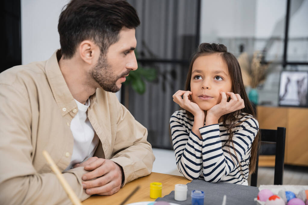 Kid talking to father near colorful Easter eggs at home  - Photo, Image