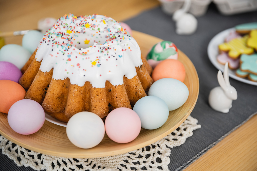 Пасхальный торт и разноцветные окрашенные яйца на тарелке дома  - Фото, изображение