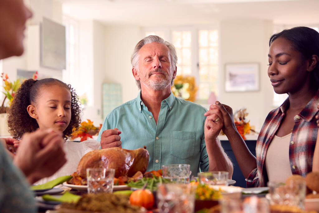 Familia de varias generaciones celebrando el Día de Acción de Gracias en casa Rezando oración antes de comer juntos - Foto, Imagen