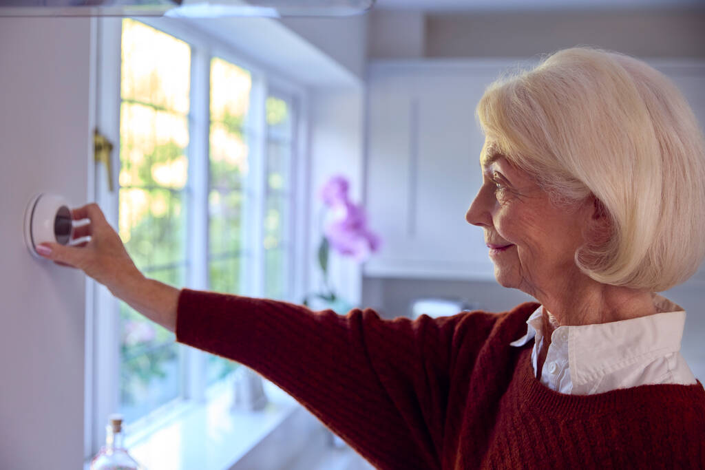 Senior Woman At Home Vypnutí ústředního topení Termostat během životních nákladů energetické krize - Fotografie, Obrázek