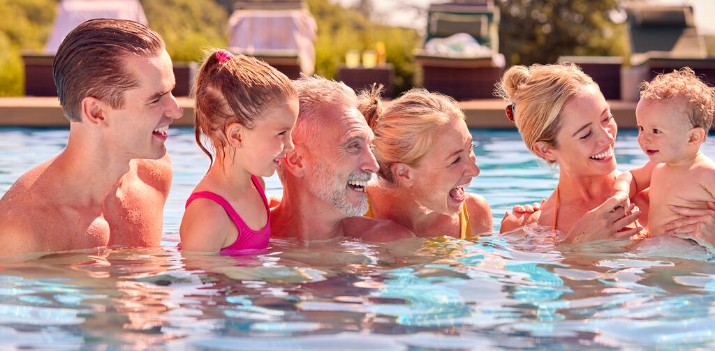 Hymyilevä monen sukupolven perhe, jossa vauva poika kesälomalla rentoutuu uima-altaassa - Valokuva, kuva