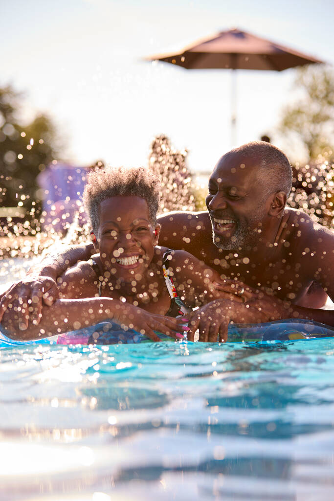 Πορτρέτο του χαμογελαστού ηλικιωμένου ζευγαριού στις καλοκαιρινές διακοπές χαλαρώνοντας στην πισίνα για Φουσκωτά - Φωτογραφία, εικόνα