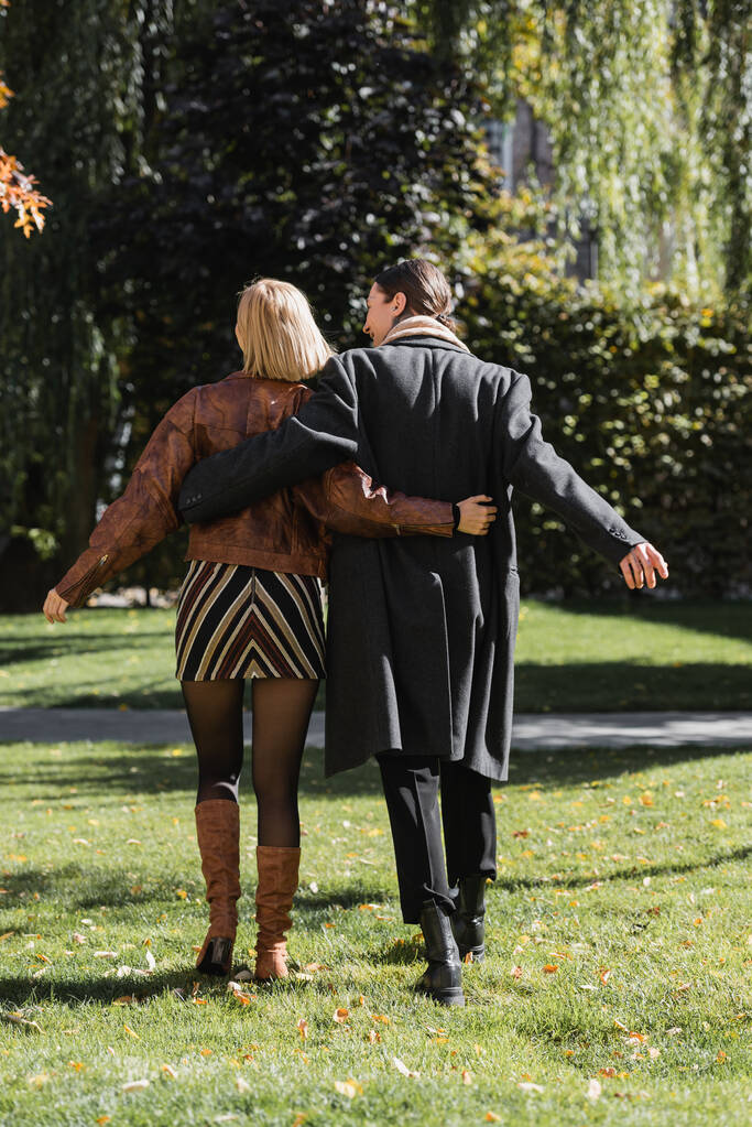 vista posteriore della giovane coppia che si abbraccia mentre cammina nel parco durante la data  - Foto, immagini