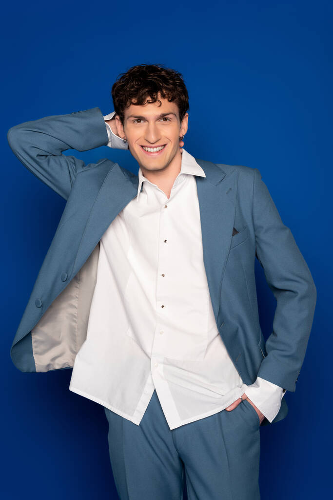Positive model in suit and shirt posing on blue background  - Photo, Image