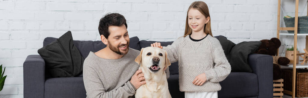 labrador chien collant la langue près de sourire homme barbu et fille préadolescente, bannière - Photo, image