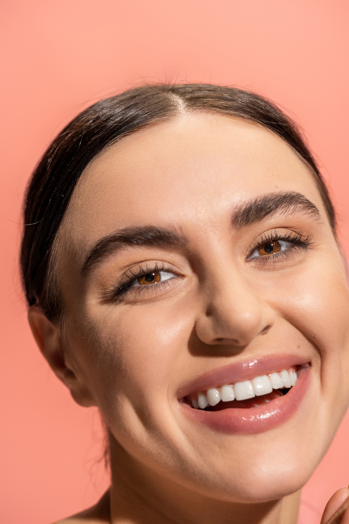 close up view of happy young woman with brown eyes looking at camera isolated on pink  - Foto, Imagen