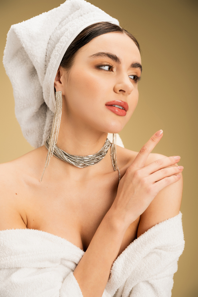 elegant young woman with makeup and luxurious jewelry looking away on beige background  - Φωτογραφία, εικόνα