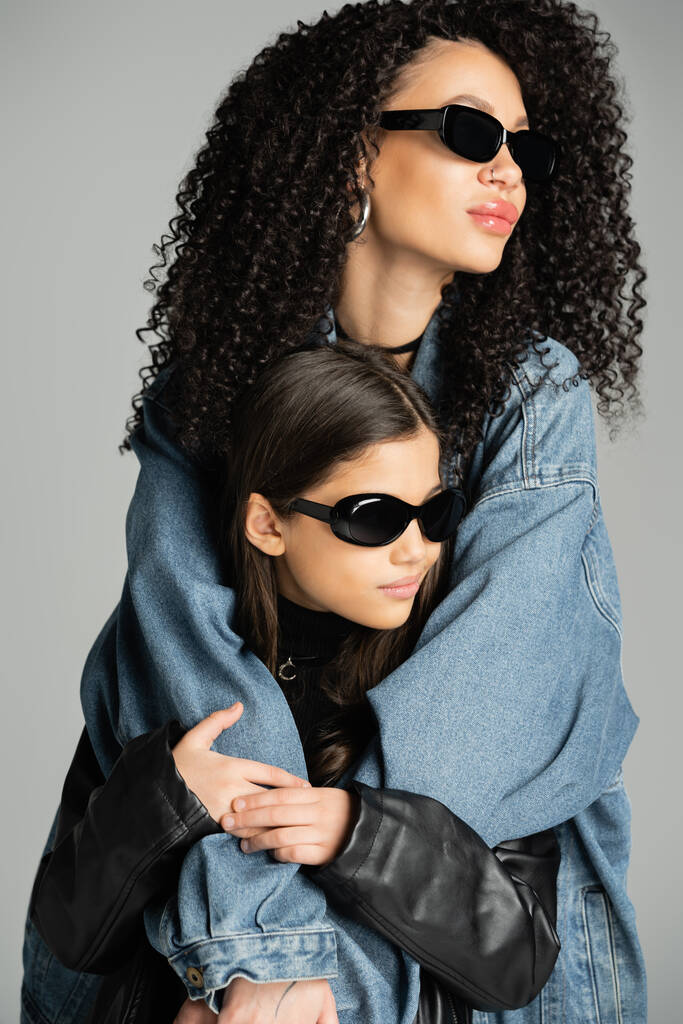 Fashionable woman in sunglasses hugging daughter isolated on grey  - Foto, immagini