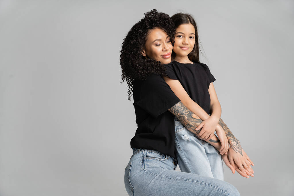 Tattooed mother hugging smiling daughter isolated on grey  - Foto, Imagen