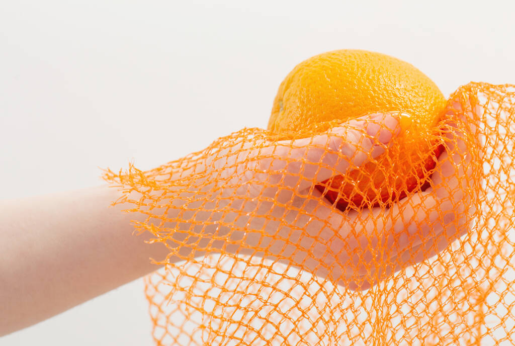 ręka samicy z pomarańczowym i syntetycznym woreczkiem - Zdjęcie, obraz