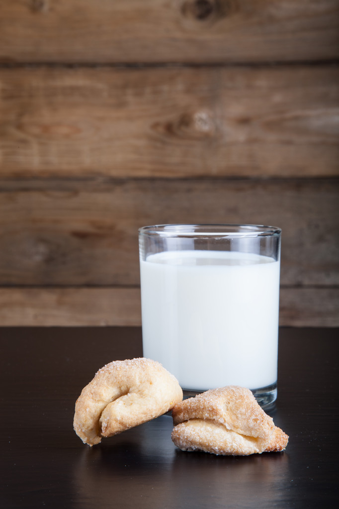 Due biscotti e un bicchiere di latte su un tavolo nero contro il vecchio legno
 - Foto, immagini