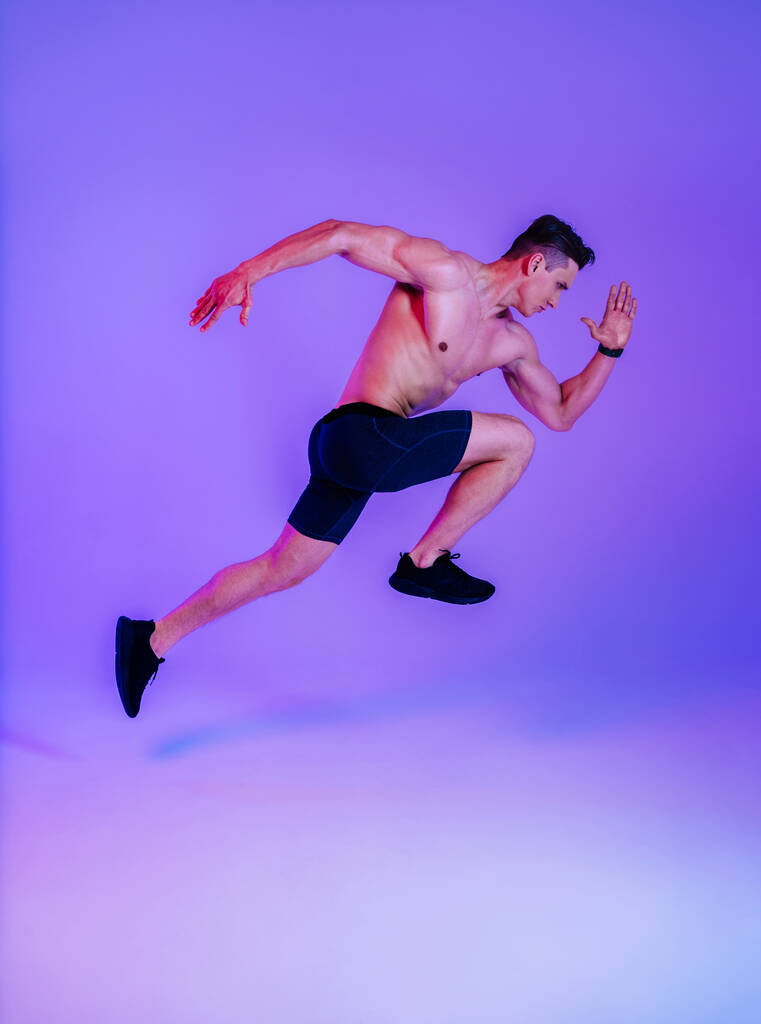 スタジオでの筋肉のトレーニングに適したアスレチックマン – ワークアウト、カラフルな照明と背景、フィットネス、スポーツ、健康ライフスタイルに関する概念を行うアクティブな男 - 写真・画像