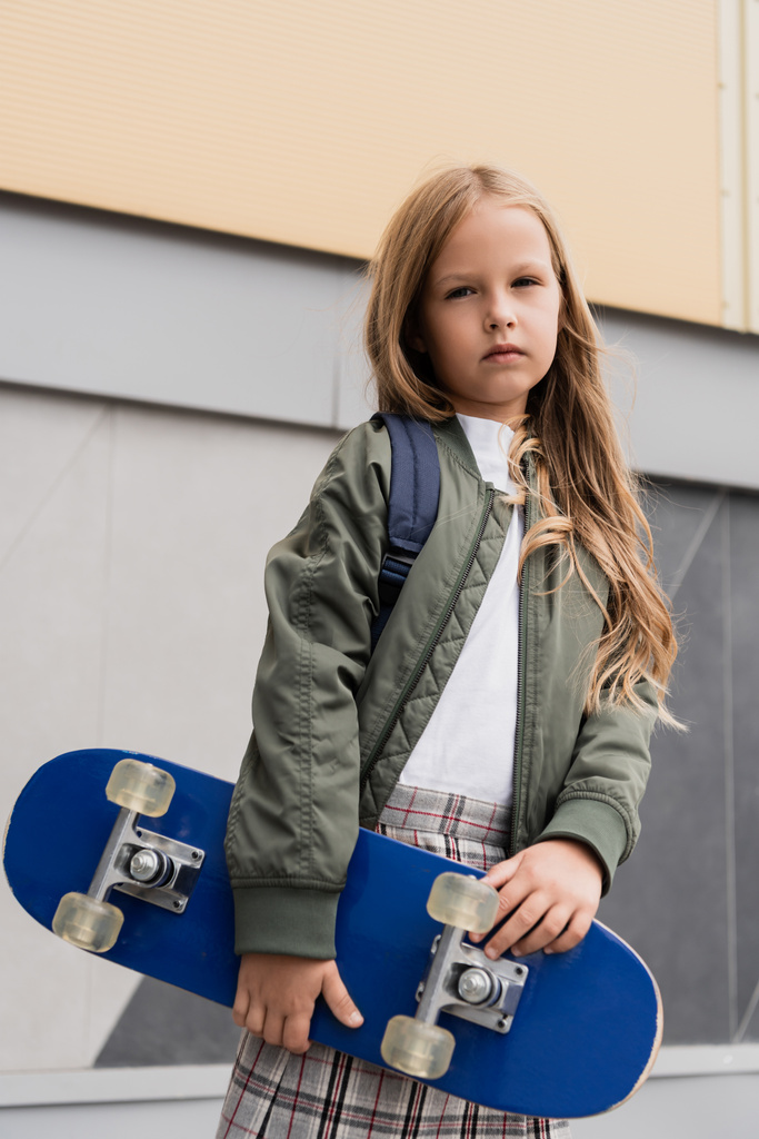 menina pré-adolescente elegante em jaqueta bomber segurando placa de centavo perto do shopping  - Foto, Imagem