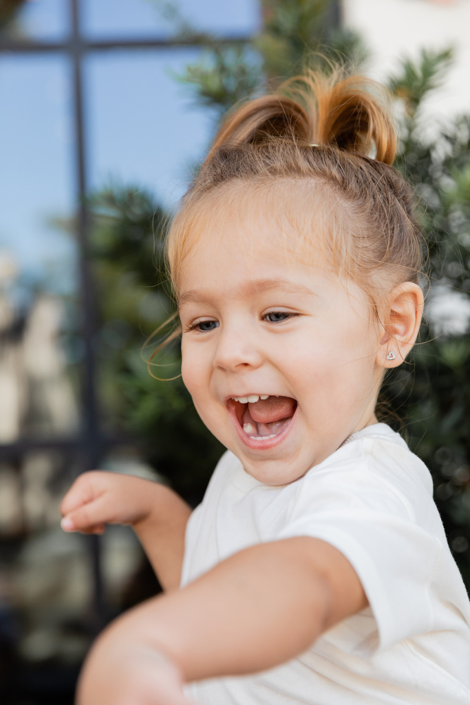 portrait of amazed toddler girl in white t-shirt laughing and looking away  - Photo, Image