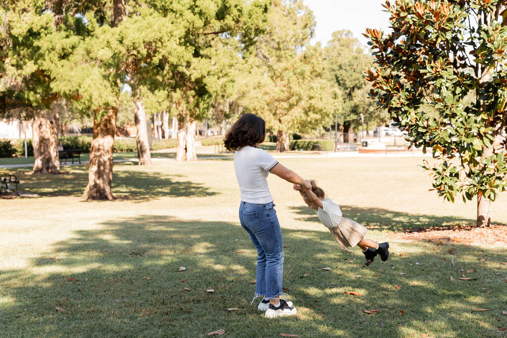 täyspitkä brunette äiti farkut leikkii lapsi tytär puistossa Miami  - Valokuva, kuva