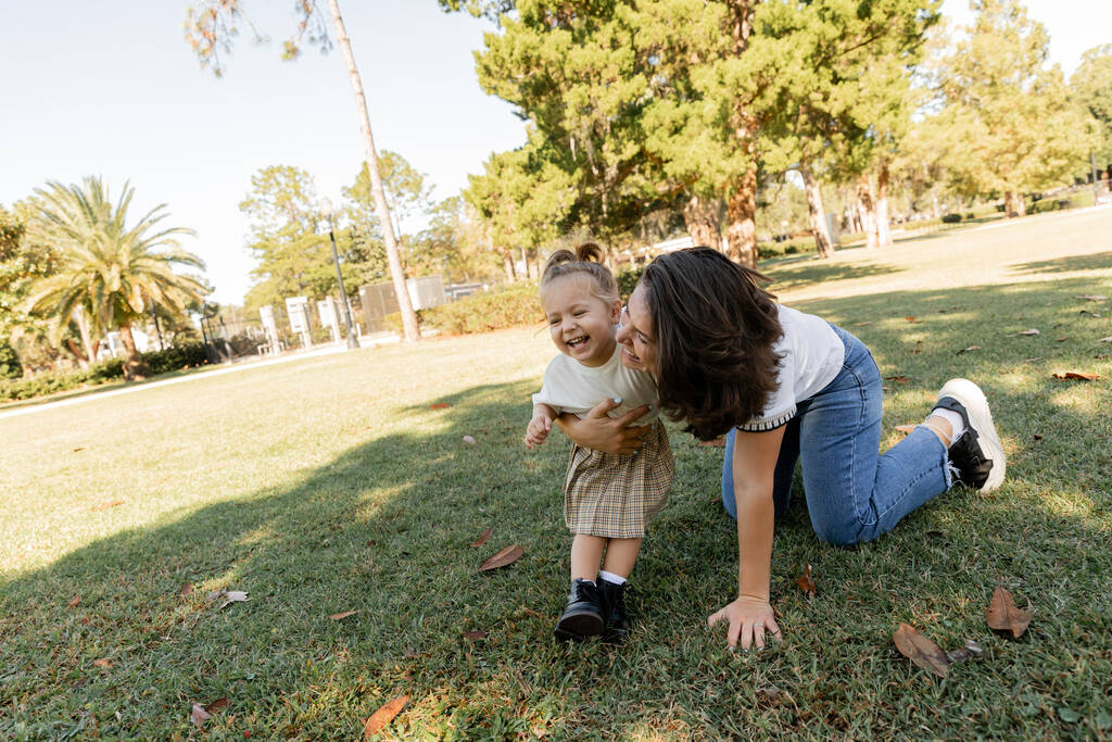 bambina che ride con la madre felice mentre gioca insieme nel parco di Miami  - Foto, immagini
