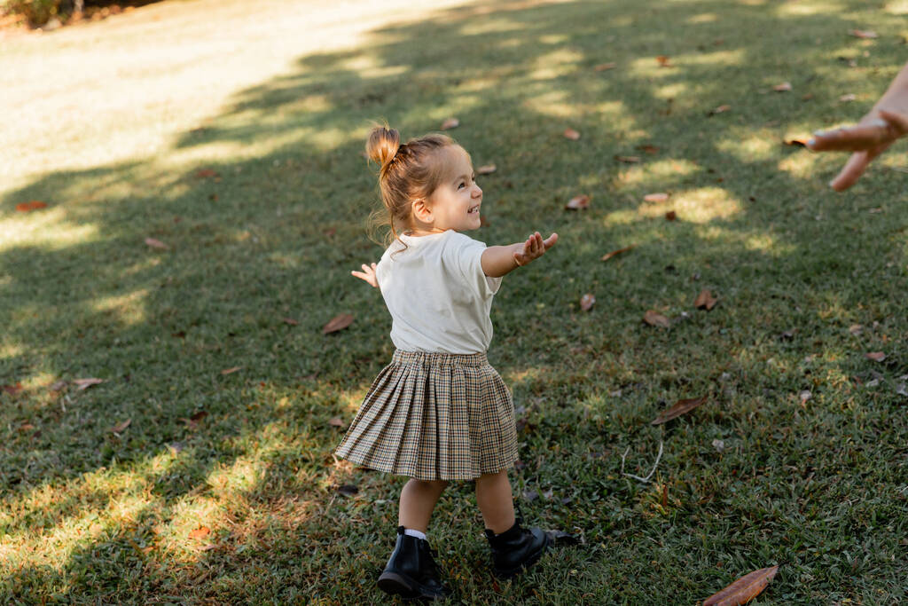 happy toddler girl standing with outstretched hands while playing in park  - Photo, Image