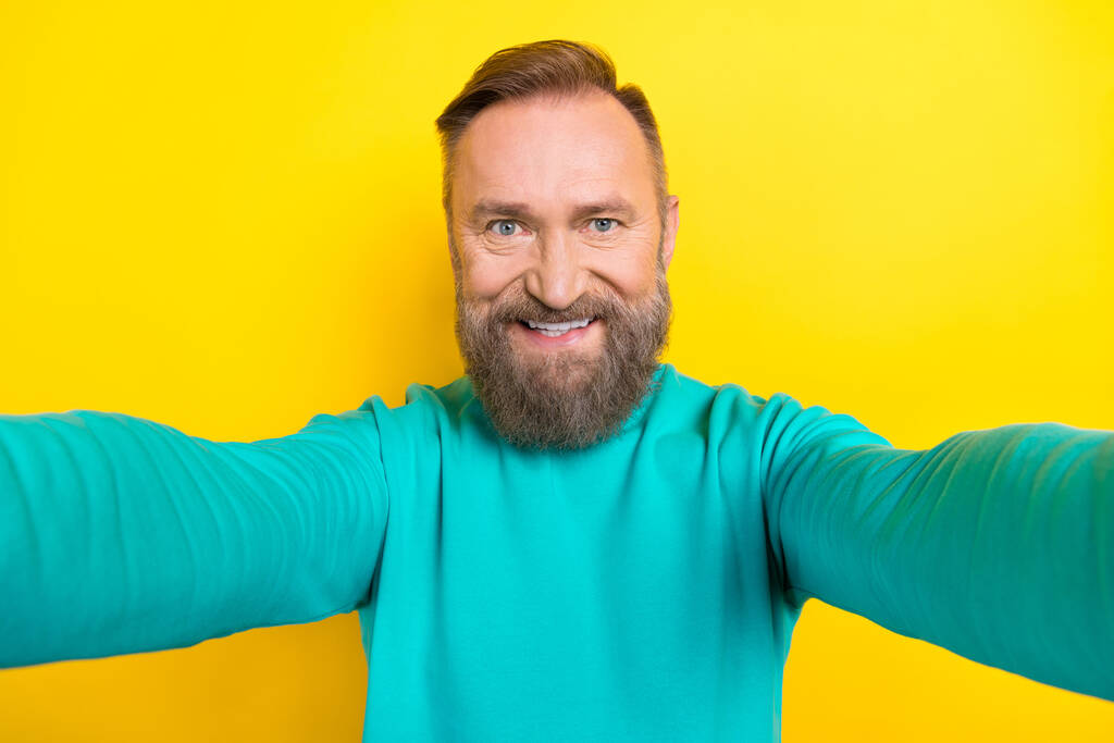 Foto retrato de atractivo abuelo tomar selfie cámara frontal alegre desgaste moderno traje de aguamarina aislado sobre fondo de color amarillo. - Foto, imagen