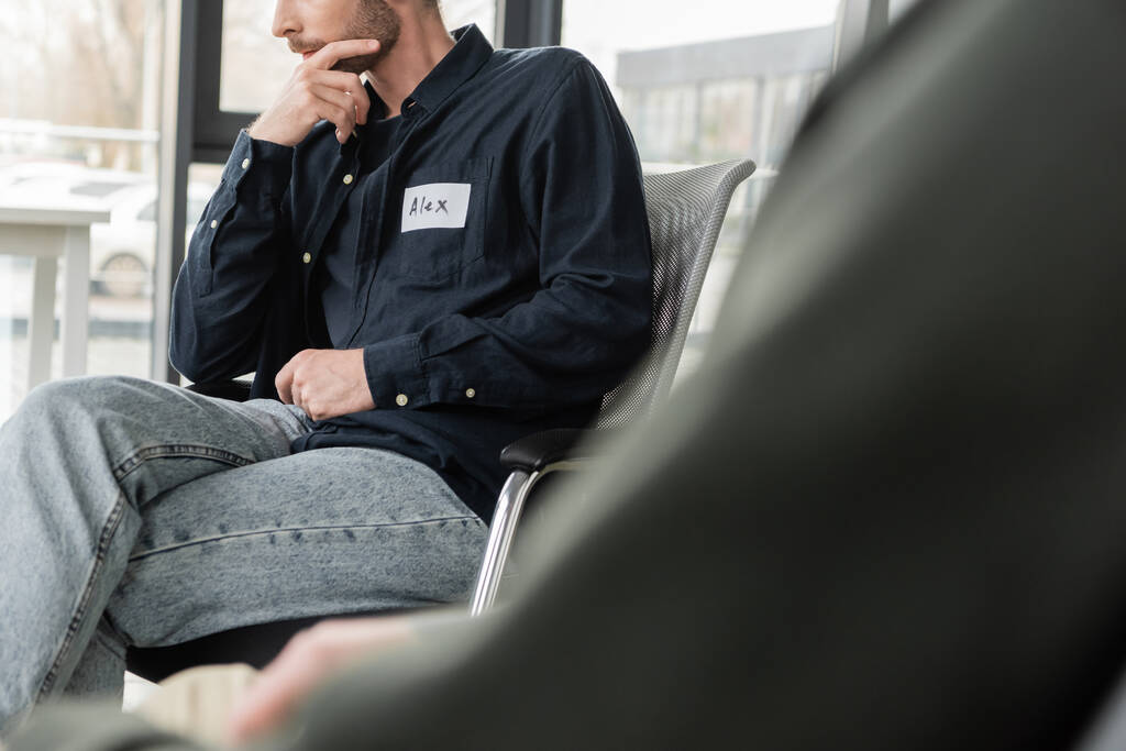 Oříznutý pohled na muže se závislostí na alkoholu sedícího na židli v rehabilitačním centru  - Fotografie, Obrázek
