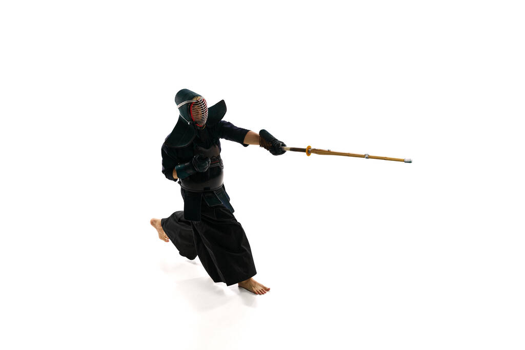 Краєвид. Людина, професійний спортсмен кендо в формі шолома з бамбуковим мечем шинай проти білого студійного фону. Концепція бойових мистецтв, спорту, японської культури, дії та руху. - Фото, зображення