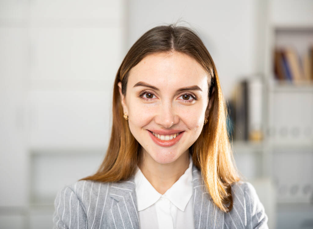 Portrét pozitivní mladé ženy kancelářské pracovnice při pohledu na fotoaparát a usmívání. - Fotografie, Obrázek