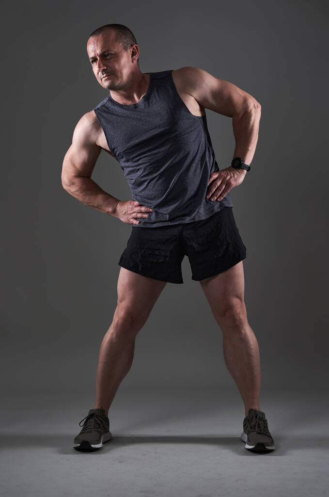 Teljes test lövés egy érett férfi csinál egy fitness edzés szürke háttér - Fotó, kép