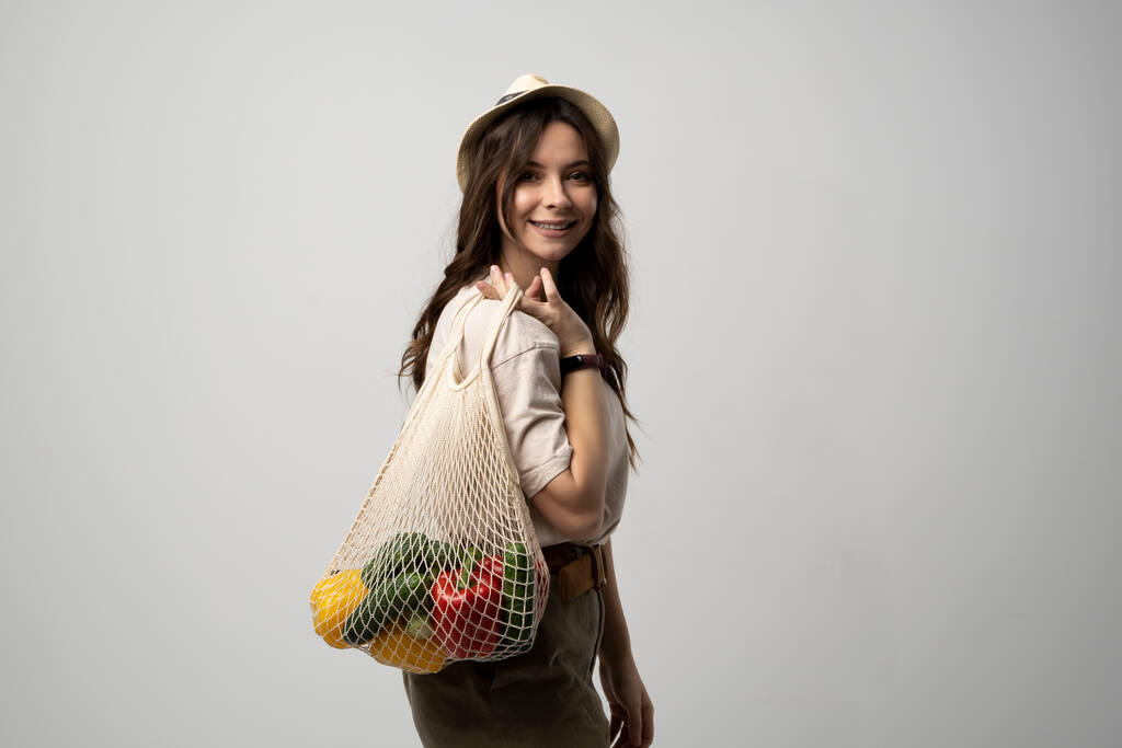 Mladá žena držící síťovaný sáček se zeleninou bez umělé hmoty. Bez odpadu, bez plastu. Ekologický koncept. Udržitelný životní styl - Fotografie, Obrázek