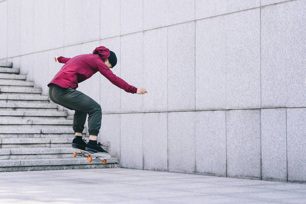 Azjatka deskorolkarka skateboarding w nowoczesnym mieście - Zdjęcie, obraz