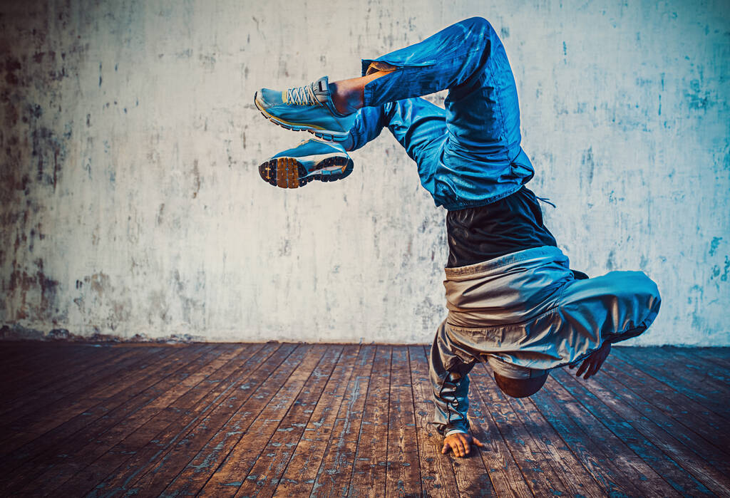 Jonge man break dancing op muur achtergrond - Foto, afbeelding