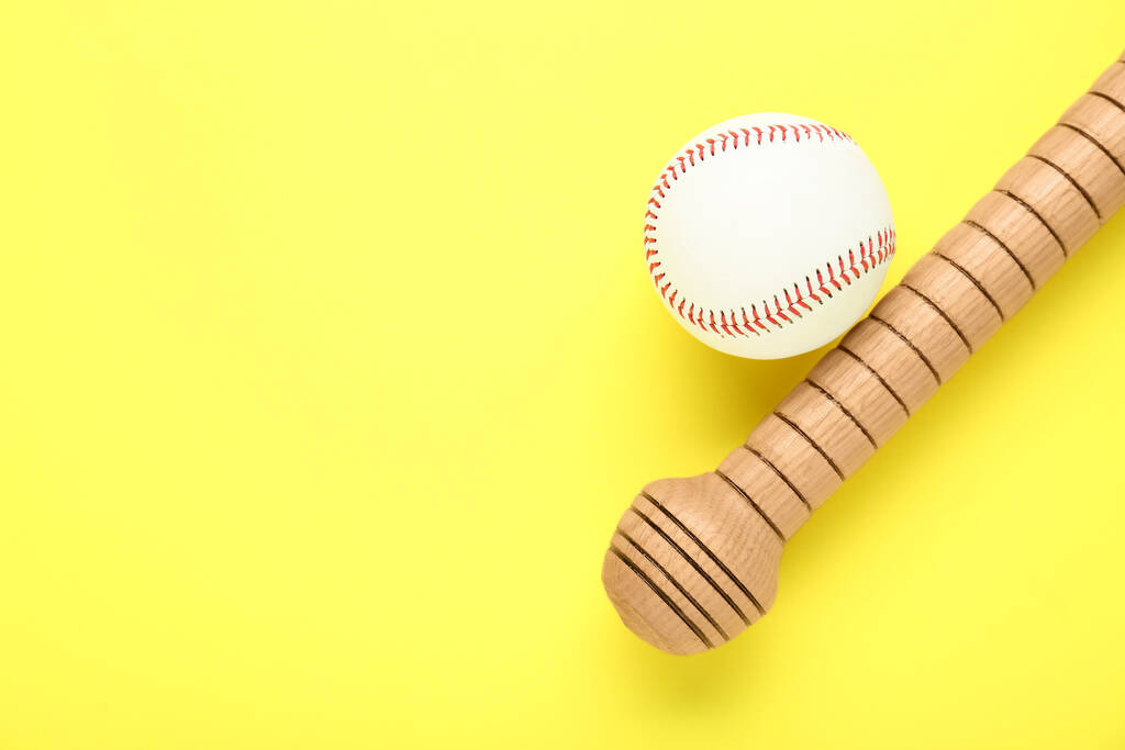 Baseballschläger und Ball aus Holz auf gelbem Hintergrund, flach liegend. Raum für Text - Foto, Bild