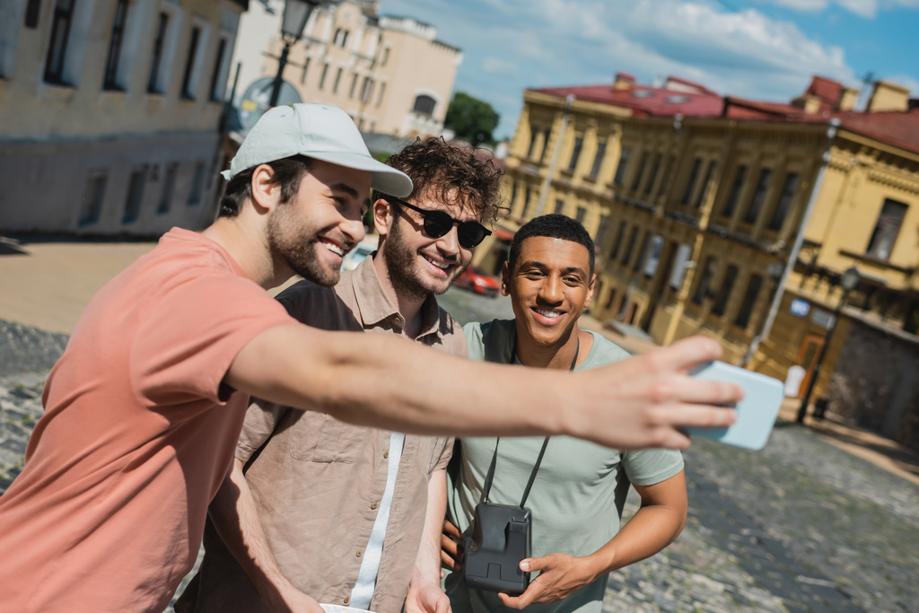 Andrews 'un Kyiv' e inişi sırasında çok ırklı erkeklerle selfie çeken mutlu turist. - Fotoğraf, Görsel