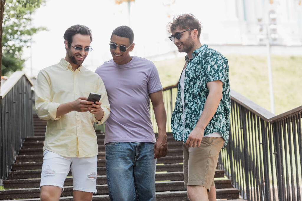 Yaz parkında merdivenlerde cep telefonu kullanan tasasız ırklar arası arkadaşlar.  - Fotoğraf, Görsel
