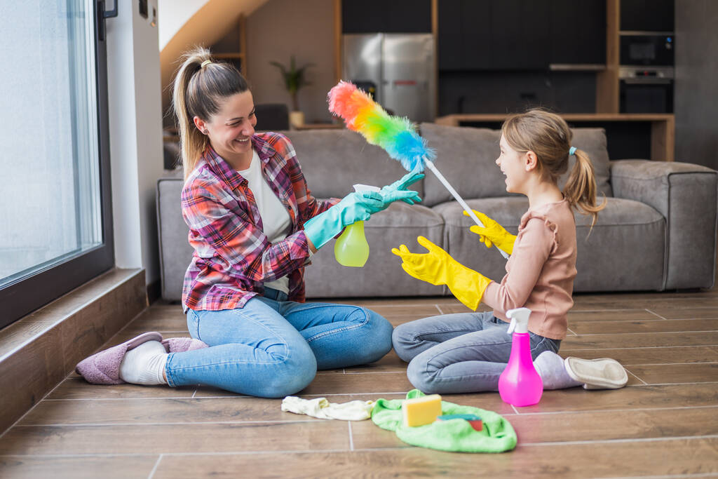 Feliz madre e hija divirtiéndose mientras limpian la casa juntas. - Foto, Imagen