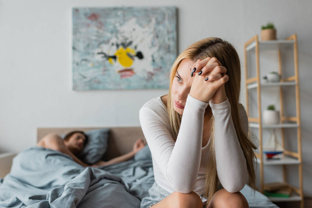 huolestunut nuori nainen istuu sängyllä yhden yön jälkeen vieraan kanssa  - Valokuva, kuva