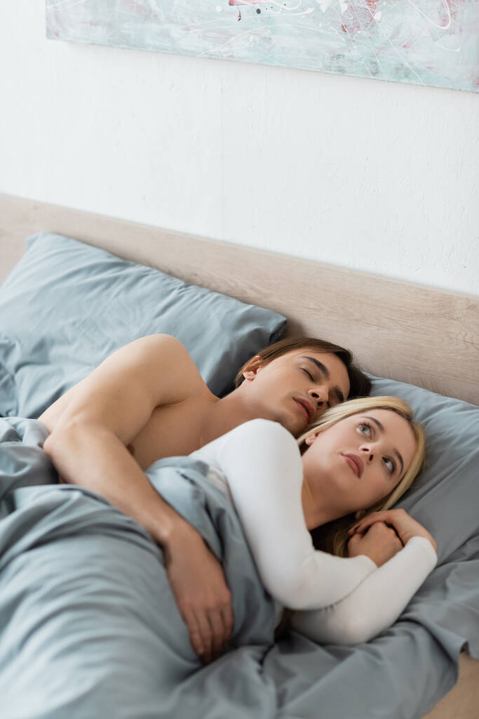 confusa donna sdraiata a letto con l'uomo addormentato dopo una notte di stand  - Foto, immagini
