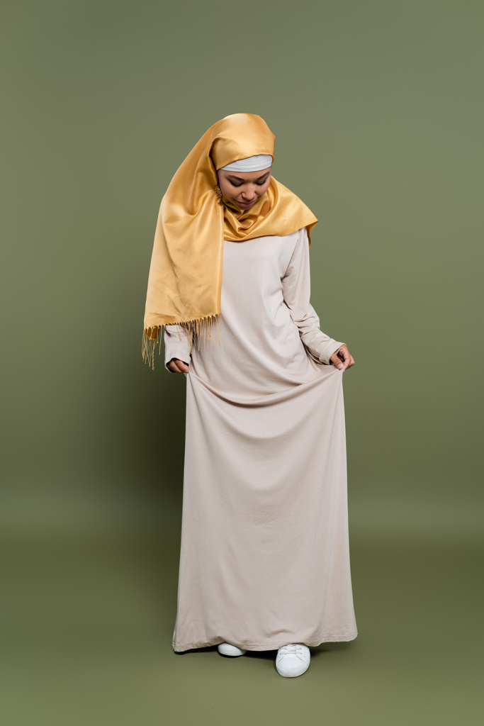 Stylový multiracial žena v hidžábu stojící v šatech na zeleném pozadí - Fotografie, Obrázek