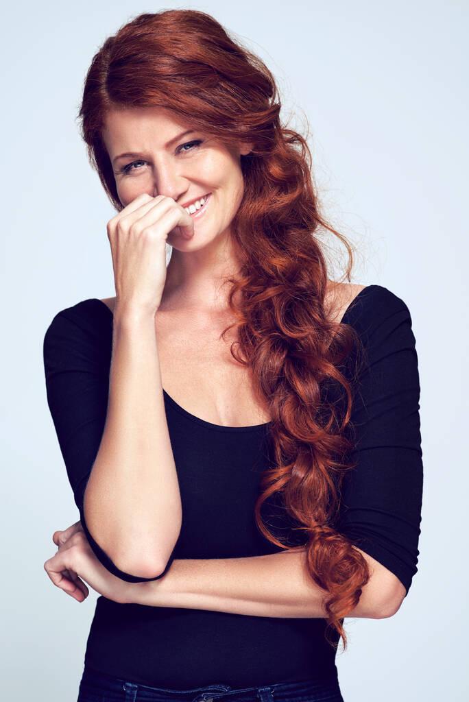 Mantenerlo rizado. Foto de estudio de una joven con hermoso cabello rojo posando sobre un fondo gris - Foto, imagen