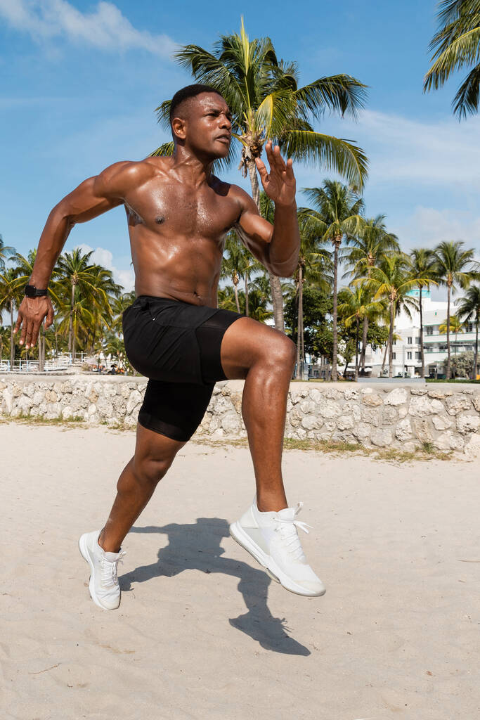 atlético afro-americano homem em shorts e tênis correndo em Miami praia - Foto, Imagem