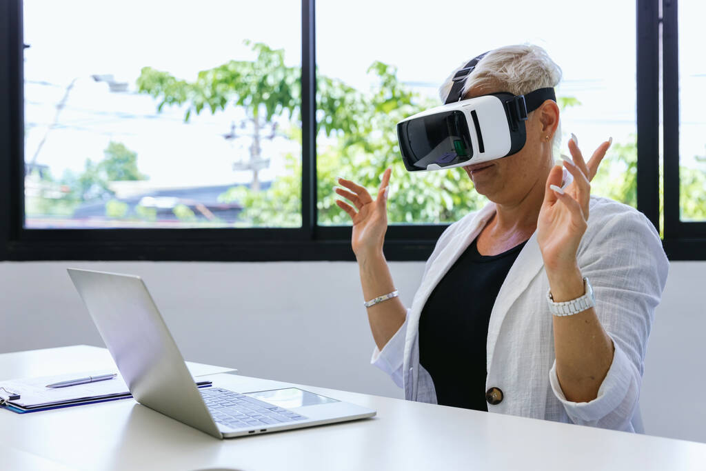 Business Woman ve VR headsetu. Žena pomocí VR brýle pro online hru. Obchodní žena sedí uvnitř kancelářské budovy s bezpečnostním rozhraním a pomocí sluchátek virtuální reality - Fotografie, Obrázek