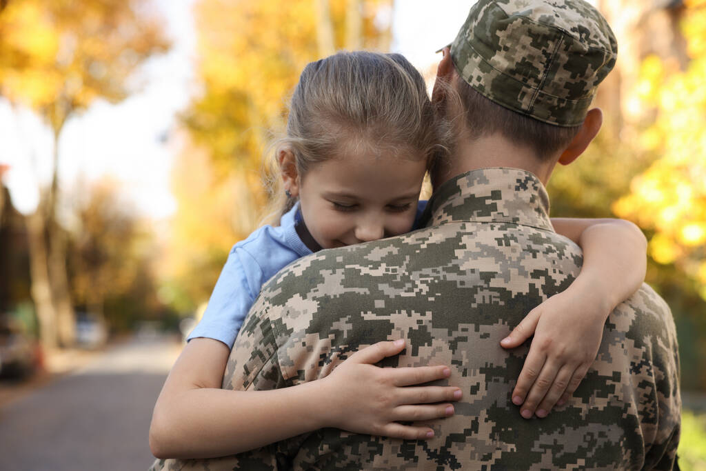 Daughter hugging her father in Ukrainian military uniform on city street. Family reunion - Fotoğraf, Görsel