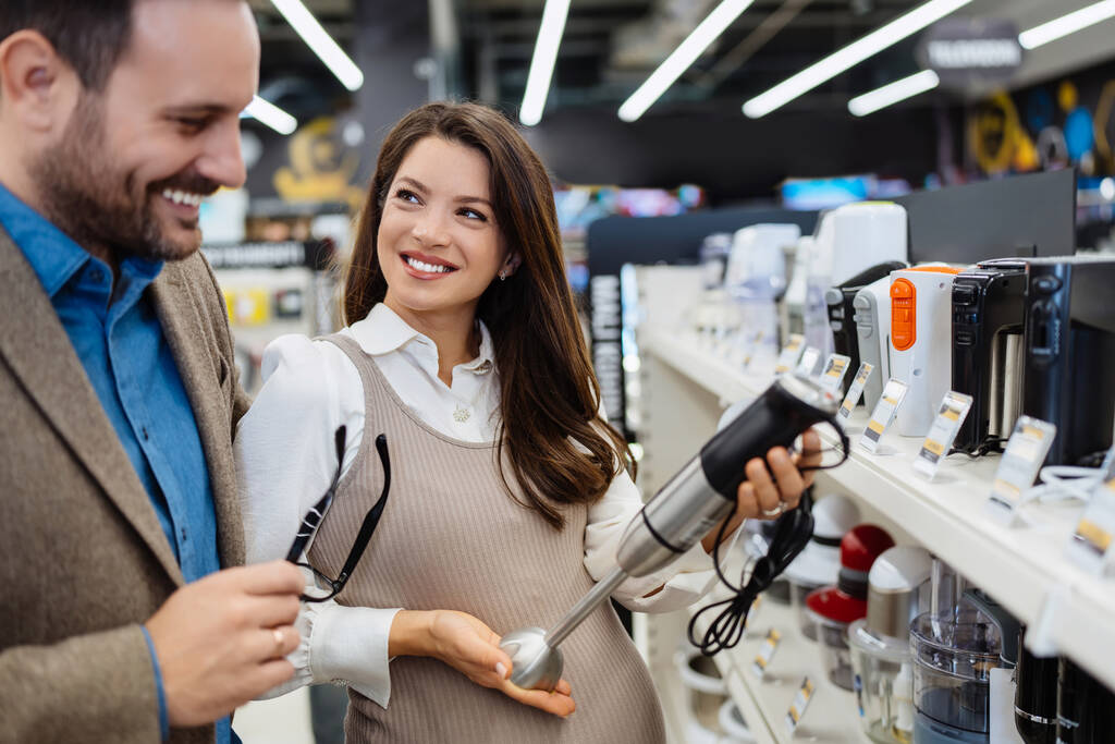 Beautiful and happy middle age couple buying consumer tech products in modern home tech store. They are choosing small kitchen appliances. People and consumerism concept. - Foto, Imagem