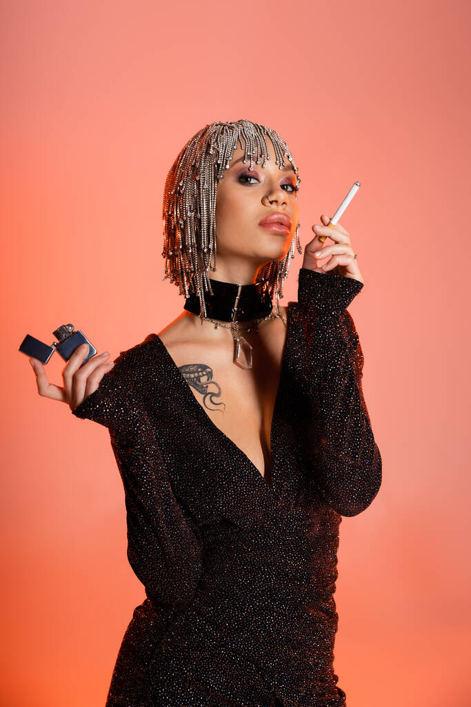 ヘッドウェアのファッショナブルな女性がタバコとライターを身に着けている - 写真・画像