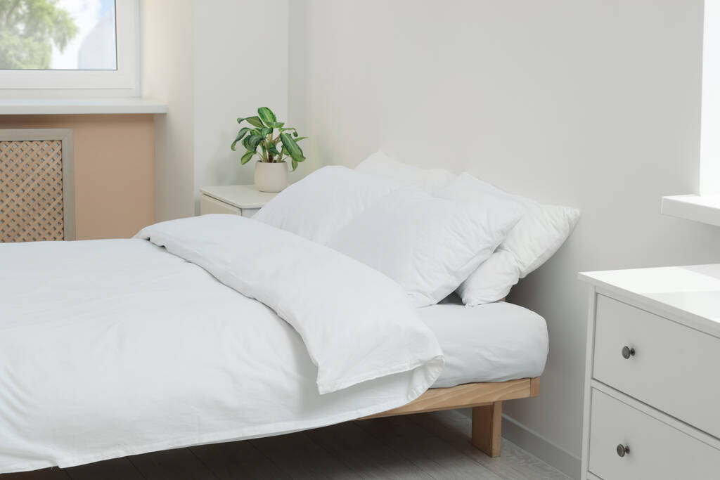 Bed met zachte witte kussens in knusse kamer interieur - Foto, afbeelding