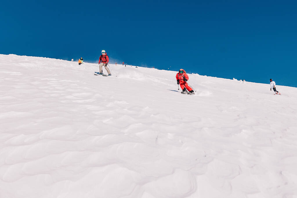 Karpaty, Ukraine, February 8, 2023. Skiers and snowboarders freeride in clear sunny weather on the slopes of the mountains near the resort of Dragobrat. High quality photo - Foto, afbeelding